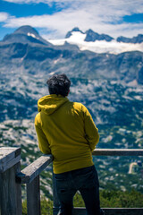 Fototapeta na wymiar Traveler at Panorama Richtung Dachstein, Dachstein Mountains and enjoys the landscape in Austria, Mountains - extreme wide panoramic. Dachstein