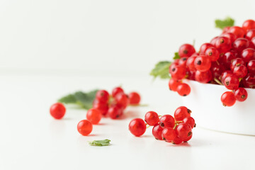 Red currant berries with green leaves isolated on the white background. Fresh summer berries