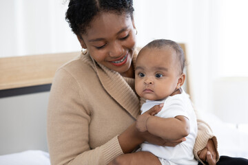 close up African young mother carrying and playing with her adorable baby on bed