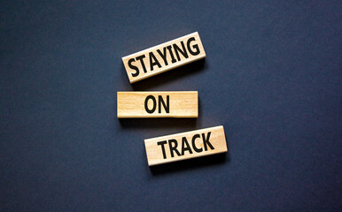 Staying on track symbol. Concept words Staying on track on wooden blocks on a beautiful black table...