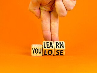 We learn or lose symbol. Concept words We learn and We lose on wooden cubes. Businessman hand. Beautiful orange table orange background. Business and we learn or lose concept. Copy space.
