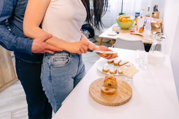 couple preparing sandwiches together, slicing bread in the kitchen