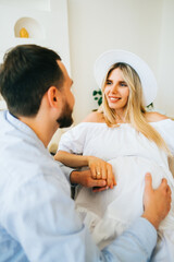 Obraz premium Future mother and father clasped pregnant big tummy. husband hugs pregnant wife. Happy family resting at home