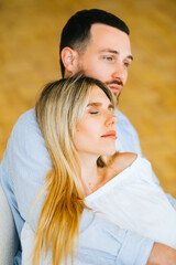 Portrait of future mother and father. Husband hugs pregnant wife. Happy family resting at home