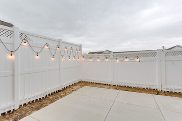 String of lights on vinyl white fencing concrete patio