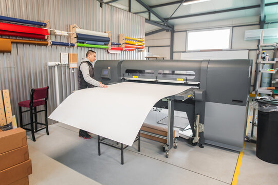 Technician operator works on large premium industrial printer plotter machine