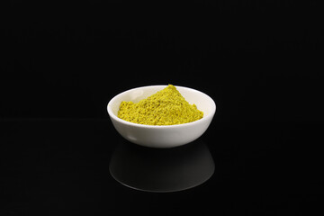 Fragrant seasoning hops-suneli in a white plate on a dark table with reflection. Close-up
