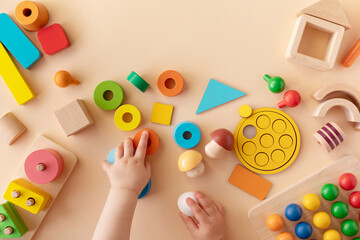Toddler activity for motor and sensory development. Baby hands with colorful wooden toys on table...