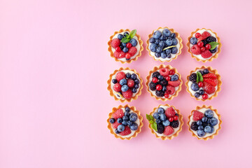 Obraz na płótnie Canvas Set of different tartlets or cake with cream cheese, honey and summer berry on pink. Pastry dessert top view. Flat lay.