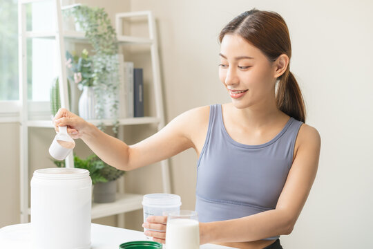 Diet meal replacement for weight loss, smile asian young woman, girl in sportswear,  hand in holding scoop making protein shake, drink supplement for muscle after workout at home. Healthy body care.