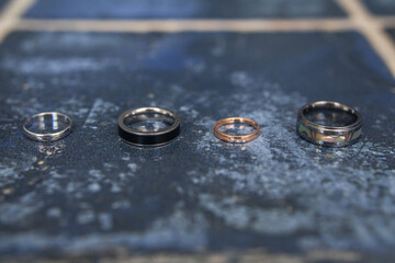 Four wedding rings on a blue tile