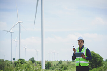 Engineer man stand holding tablet front the wind turbines generating electricity power station. Concept of sustainability development by alternative energy