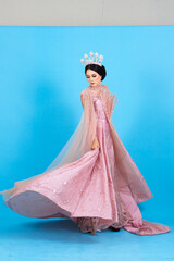 Obraz premium Portrait of asian woman in beautiful makeup wearing pink wedding dress, isolated on blue background.
