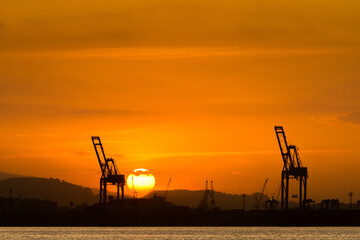 Industrial Cranes in the Horizon With Sun Setting Behind