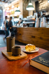 Morning coffee and peach pie in a modern cafe with a book on the table and a blurred counter in the background