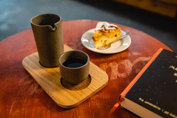 Morning coffee and peach charlotte in a bakery with a book on the side of the table