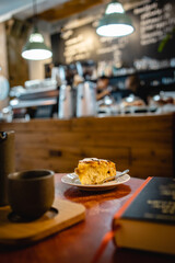 Vertical closeup shot of the peach cake in a loft cafe with coffee and book on the side