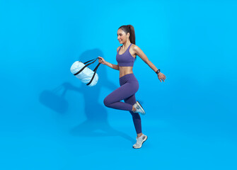 Fototapeta na wymiar Go to training fitness. Happy Asian sporty woman with bag running on blue background. Sports and healthy lifestyle