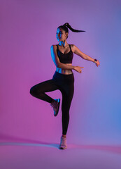 Fototapeta na wymiar Athlete asian sportswoman jumping dance as part of fat burning workout in fitness studio neon background. Woman exercising with cardio at the gym.