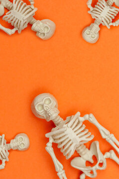 Composition with skeletons on an orange background.Funny Halloween concept. vertical photo