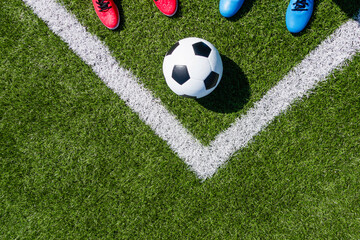 Soccer football background. Soccer ball and two pair of football sports shoes on artificial turf soccer field. Top view