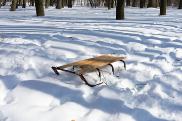 Children's sleds are standing in the snow near the forest