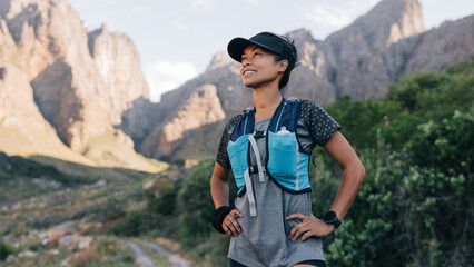 Naklejka premium Young female standing in valley looking on mountains after hike. Woman in sportswear looking on mountains trail.