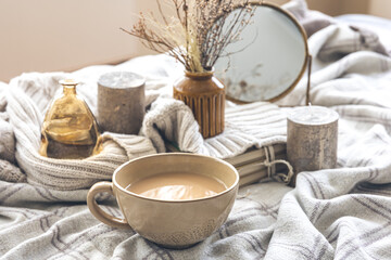 Cozy autumn composition with a cup of coffee and candles in bed.
