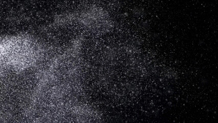 Abstract animation of small white particles exploding isolated on black background. Animation. White dry inks dust flying into the sides in the dark.