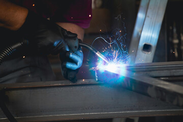 Industry worker welding iron pieces at work