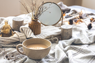 Cozy autumn composition with a cup of coffee and candles in bed.