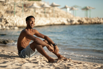 Fototapeta na wymiar Handsome and confident, outdoor smiling portrait of relaxing young african egyptian man traveler on the beach.