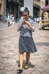 A young woman walks with a smartphone in the city.