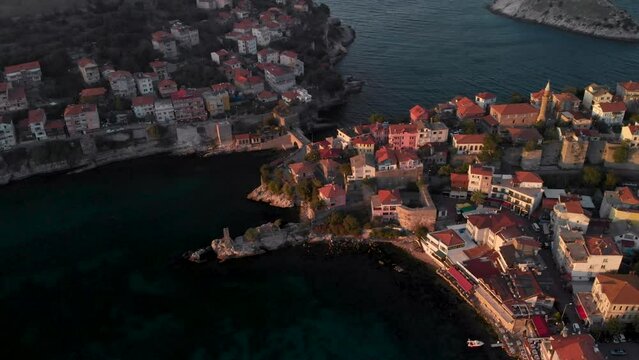 Aerial slide shot of Amasra city, Bartin province, Turkey. Sun illuminating red rooftops on seaside