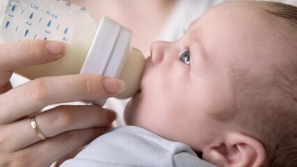 loving mother feeding her little boy child with milk baby bottle at home, portrait infant Baby eating, drinking powdered milk