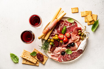 Appetizers with differents antipasti, charcuterie, snacks and red wine on white background....
