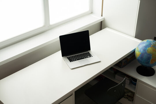 Horizontal photo of minimal workplace with computer laptop on white desk.