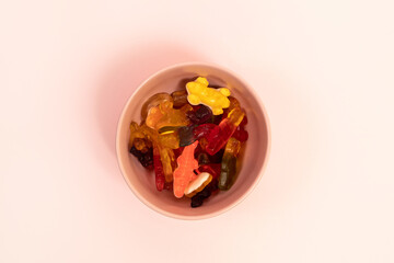 Colorful gummy candies in a pink cup on pink background