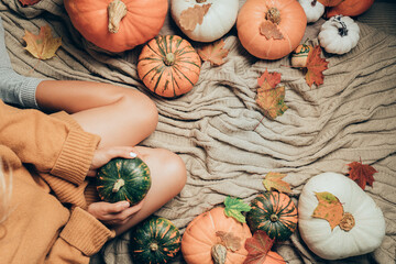 autumn background with woman sitting between pumpkins, top view