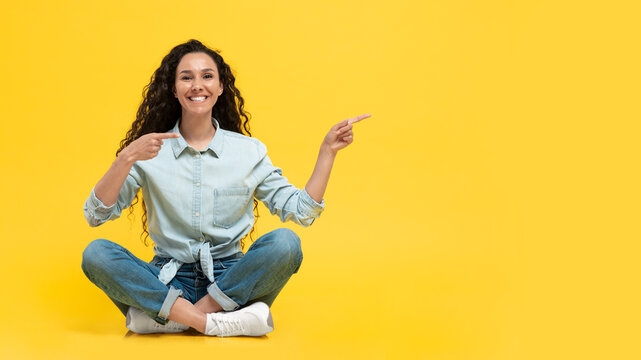 Woman Pointing Fingers Aside Sitting Over Yellow Background, Panorama