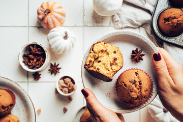 Homemade autumn pumpkin muffins with cinnamon and chocolate on tile background, top view