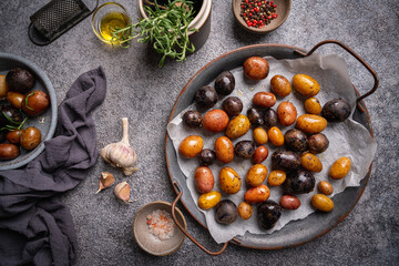 Various varieties of baked new colorful, white, red and purple potatoes on gray background, top view