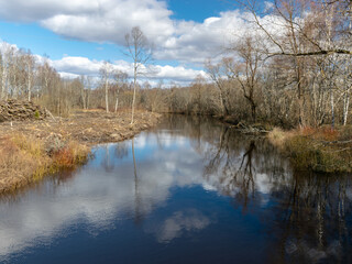 river view from the bridge, small river in early spring, blue sky and reflections in the water
