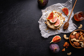 Fototapeta na wymiar Brie cheese on a wooden Board with fresh figs and honey over dark table, top view