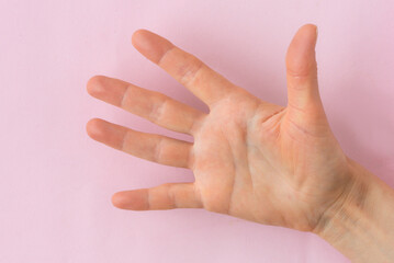 Top view of the palm of an adult hand on a pink background