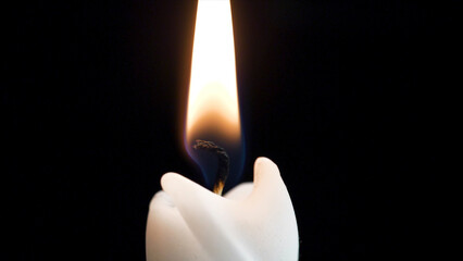 Close up detail of white wax lit candle flame and wick on isolated black background. andle lights macro. closeup of burning candle isolated on black background one flame at night macro brightly in