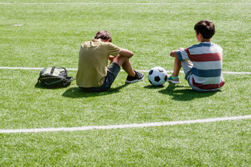 Children talking in school stadium outdoors. Teenage boy comforting consoling upset sad friend....