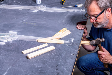 Worker adds shims leveling new pool table slate