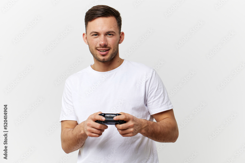 Wall mural Smiling cheerful tanned handsome man in basic t-shirt enjoy cool game with joystick gamepad posing isolated on over white studio background. Copy space Banner Mockup. Gamer RPG concept