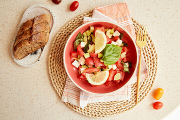 Vegetarian vegetable fresh salad of cucumbers, tomatoes, feta cheese, basil and lemon close up. Healthy food dinner. Copy space.
